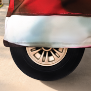 Close-up of a car tire with a red fender and white strip on a driveway.